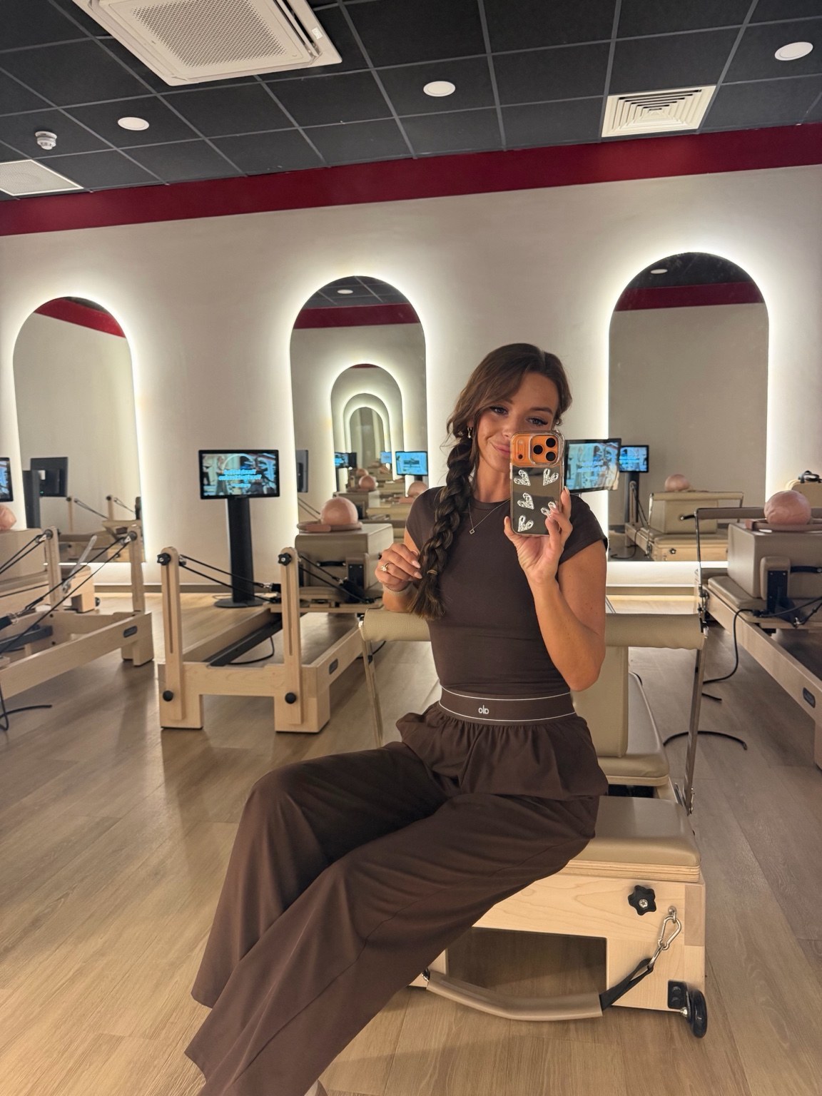 Kelly, founder of Core Haus, seated on a Pilates reformer
